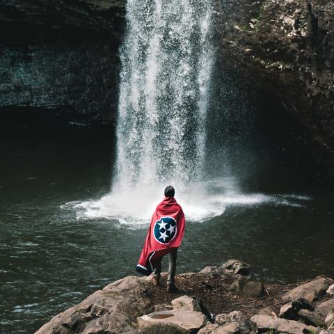Man in front of Foster Falls with Tennessee state flag